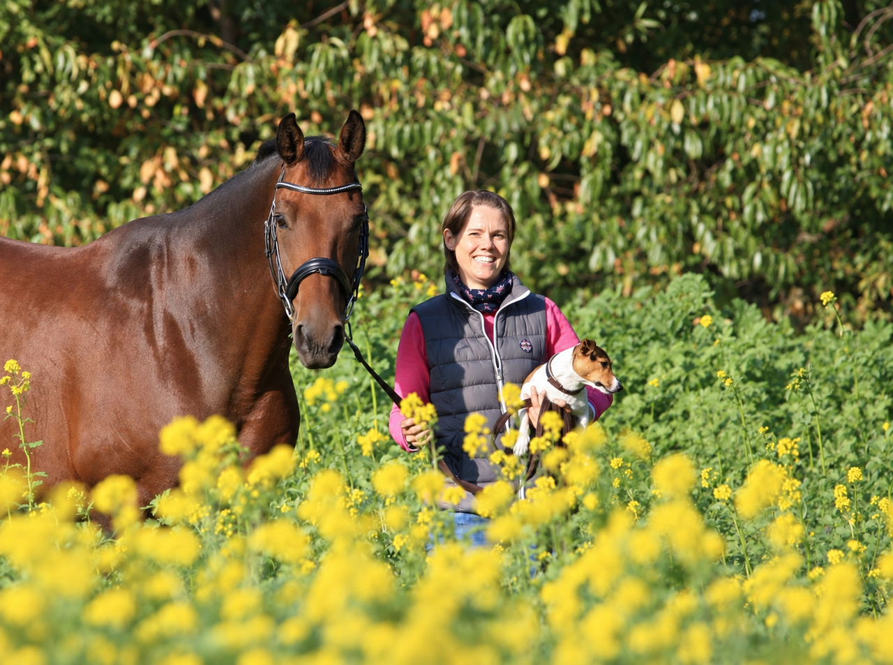 Julia Hill mit ihrem Pferd und einem Hund auf einer Wiese